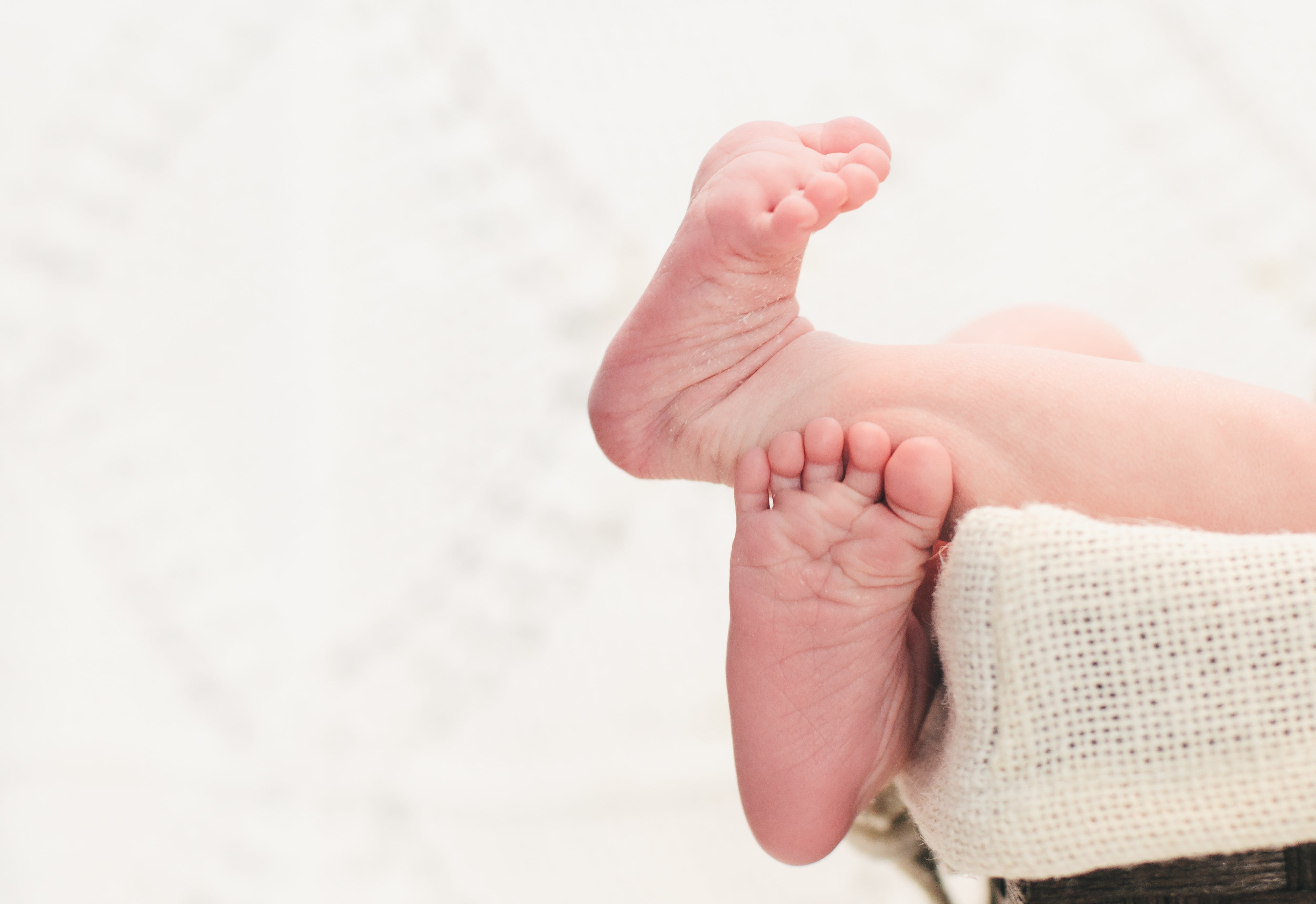A newborn’s tiny feet, held in a parent’s hands