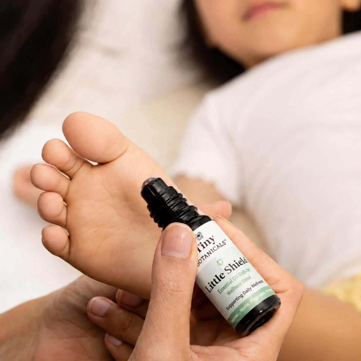 Tiny Botanicals Little Shield roll-on applied to a child's foot for daily immune support and wellness
