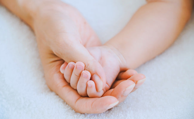 A parent's hands gently holding a baby's feet